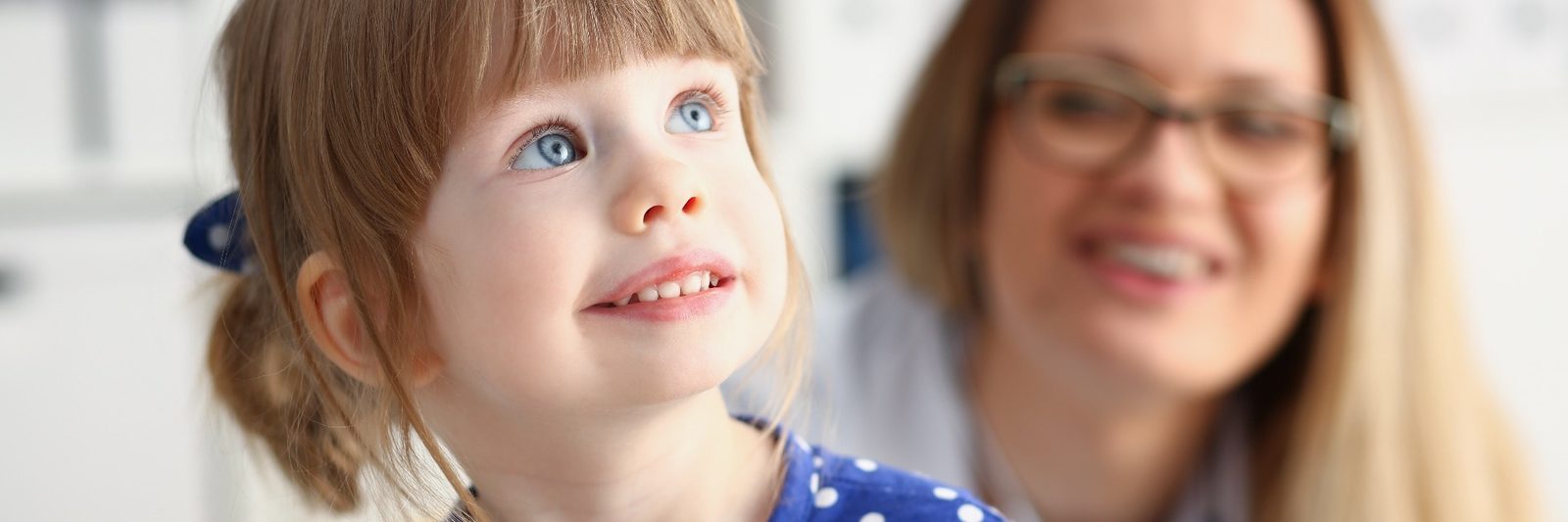 A young girl looking up and smiling at a clinician during a session