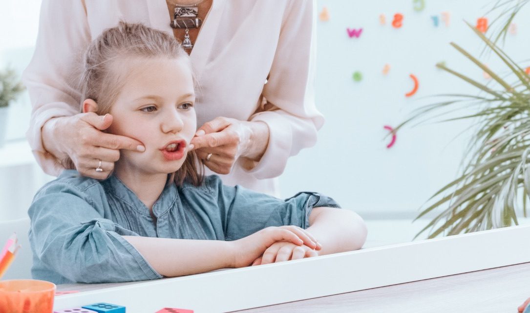 A therapist gently supports a child's jaw and cheeks during an oral motor exercise